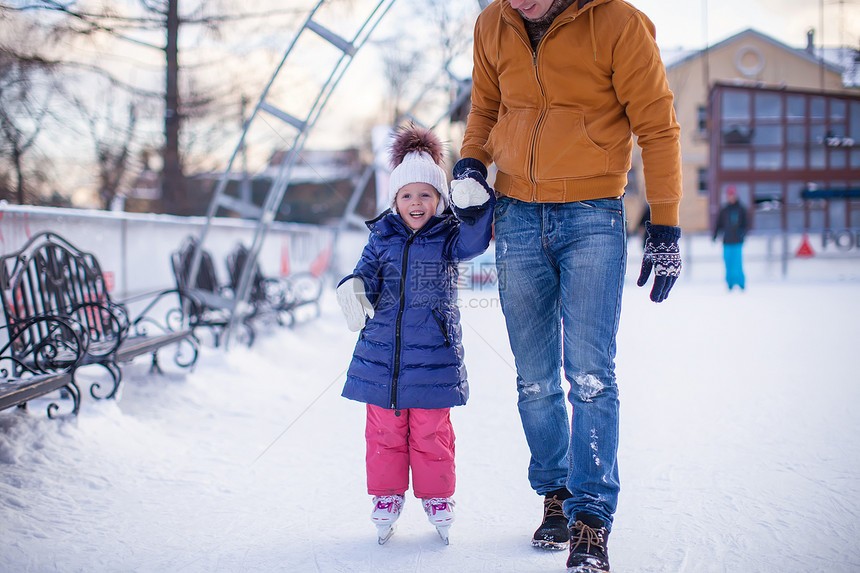 可爱的小女孩和年轻爸爸 在滑冰场上关紧家庭教育小姑娘溜冰场婴儿教学微笑帮助娱乐童年图片