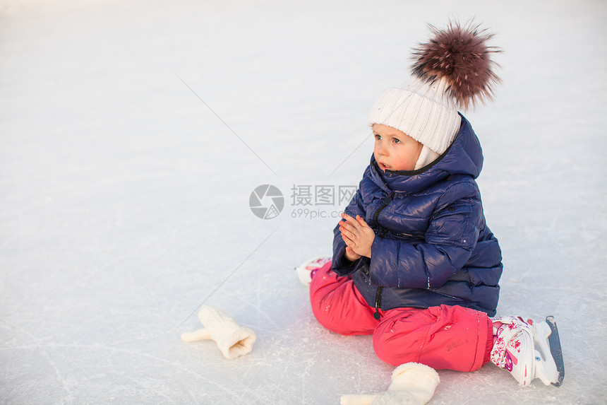 秋天后 可爱的小女孩坐在冰上 穿着溜冰鞋坐着冰雪爱好训练女孩速度女性溜冰者女儿手套小姑娘滑冰场图片