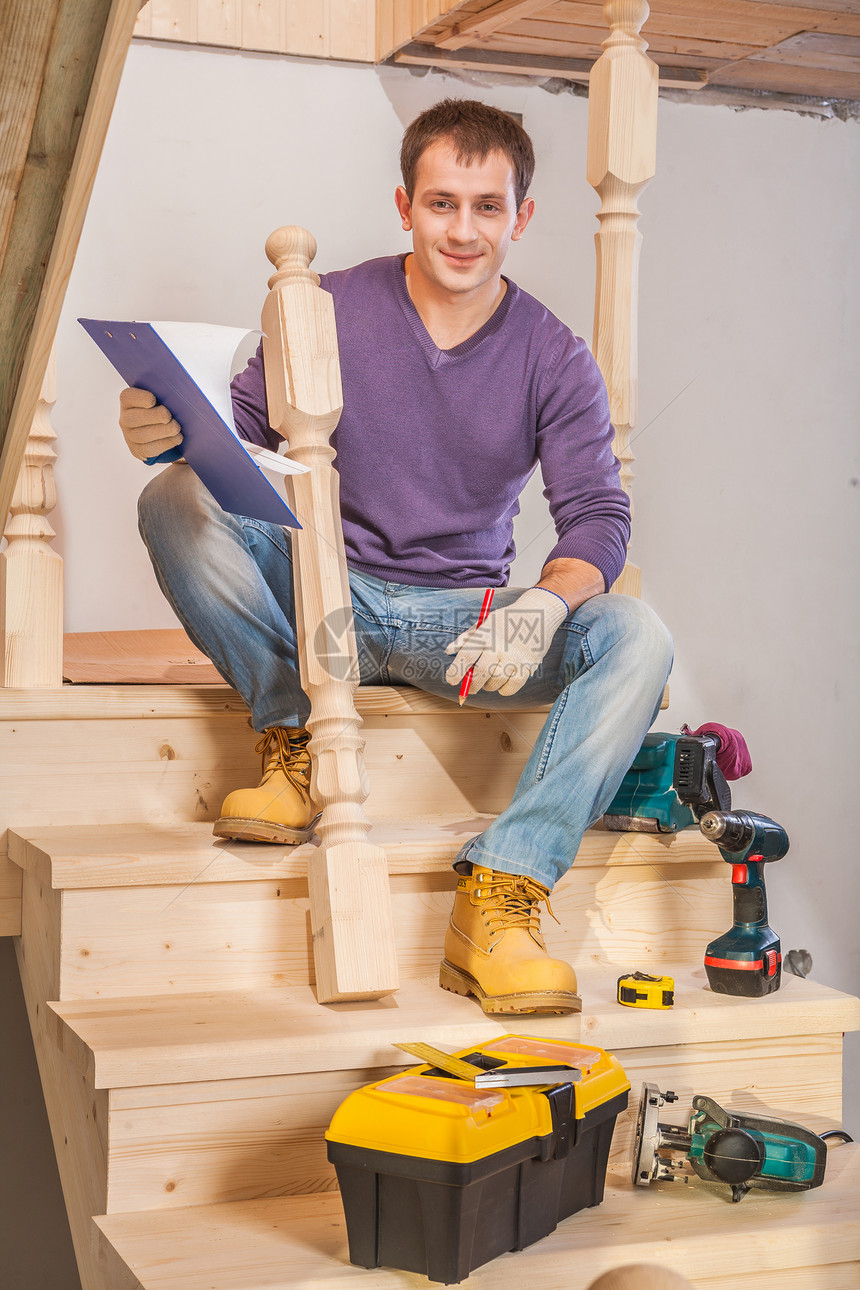 青年木匠坐在梯子的阶梯上 带工具图片
