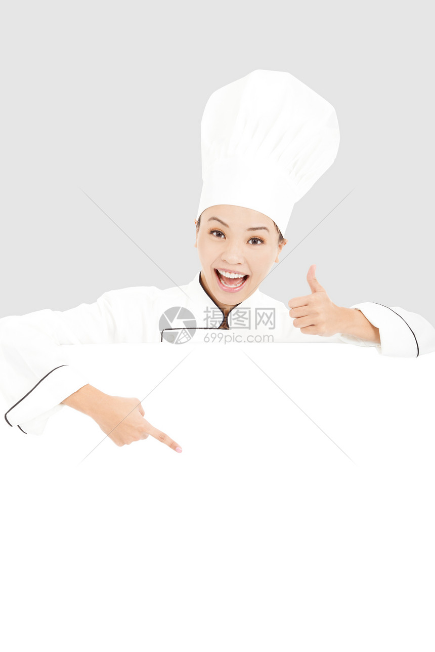 年轻女厨师微笑和用空白板指着大拇指图片