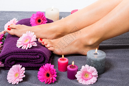 紫色毛巾被鲜花包围的女人的赤脚毛巾女性女士紫色修脚呵护搪瓷高架保养治疗背景