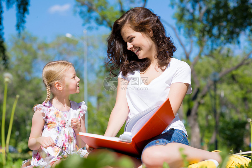 女孩和年轻女子一起阅读一本书幸福喜悦学生童年场地成人托儿所老师乐趣公园图片