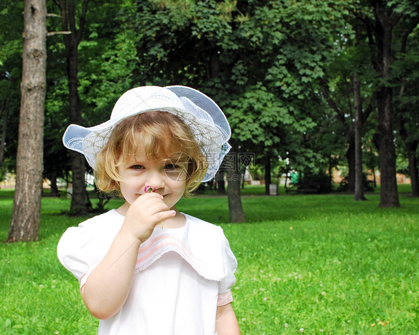 身着白裙子和帽子春季的美丽的小女孩图片