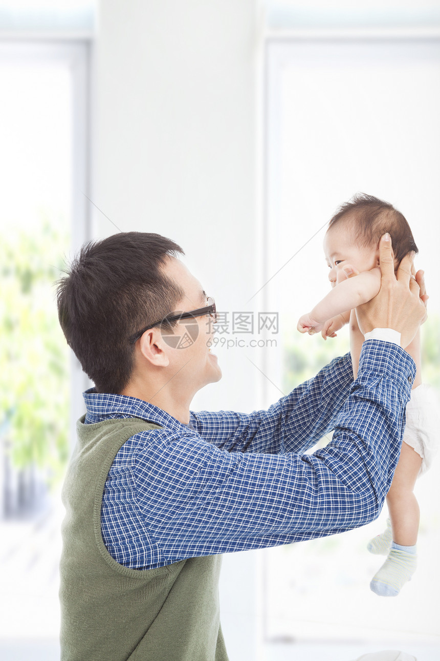 快乐的父亲在家拥抱他微笑的儿子孩子享受家庭幸福生活毯子婴儿成人父母童年图片