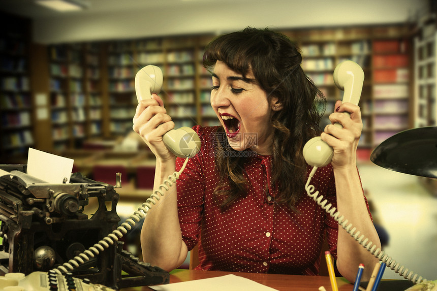 20世纪60年代 穿着红裙子的年轻女青年 绝望无依无靠 双手两只电话在办公室图片
