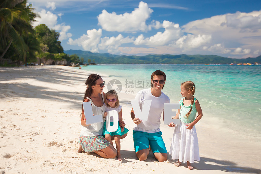 年轻家庭和两个孩子在热带度假时 有爱字词母亲父亲女儿喜悦旅游男性享受女孩成人海洋图片