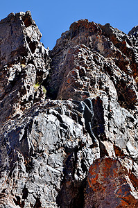 青年男子登山远足石头男人男性活动顶峰悬崖挑战岩石蓝色背景图片