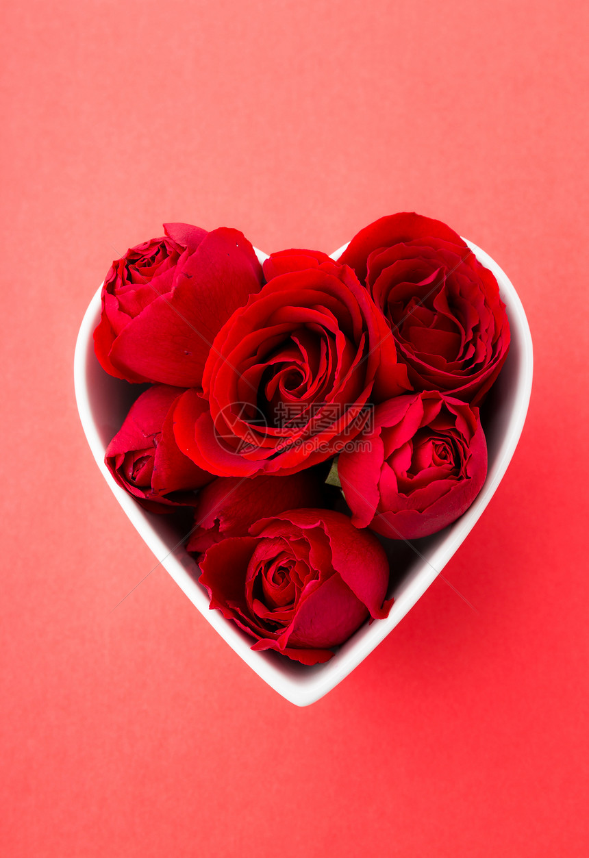 红玫瑰在心脏形状的碗里 有红色背景图片