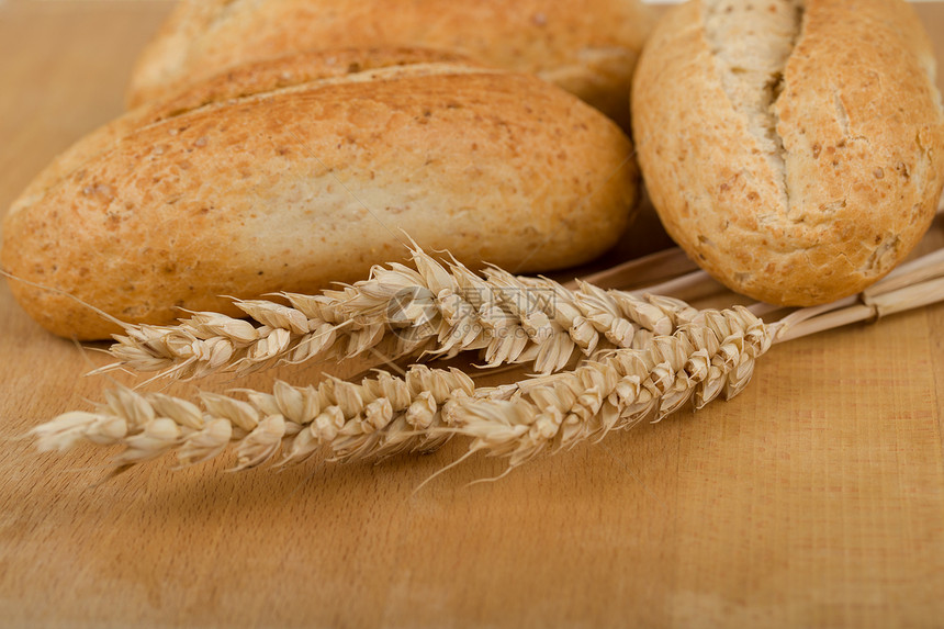 木桌上滚动着麦子的耳朵粮食收成饮食桌子小麦种子燕麦脆皮棕色面包图片