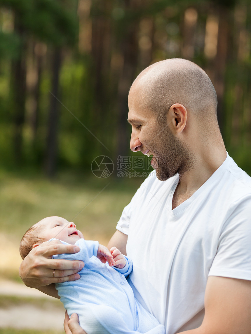 父亲和新生儿儿子在户外步行图片
