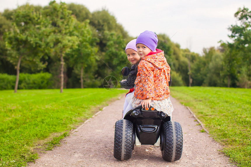 在绿色公园骑摩托车的可爱小女孩肖像 在绿色公园中女孩乐趣裙子引擎快乐公园自行车晴天夹克喜悦图片