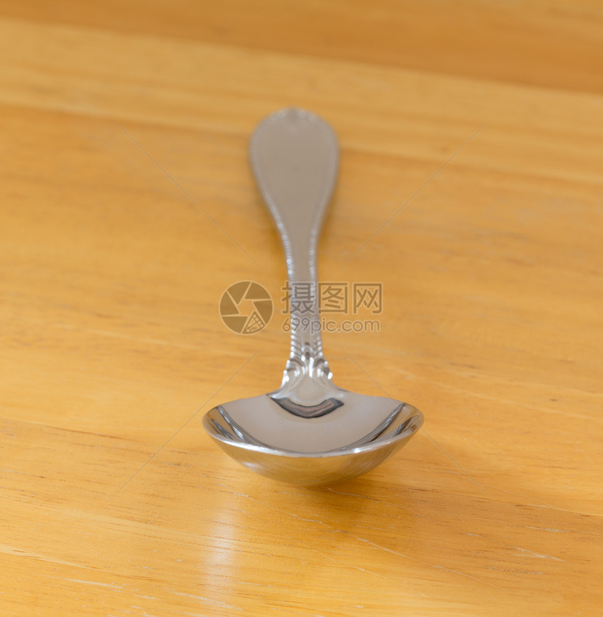 木柴上不锈钢勺子服务白色桌子厨具银器工具用具木头反射图片