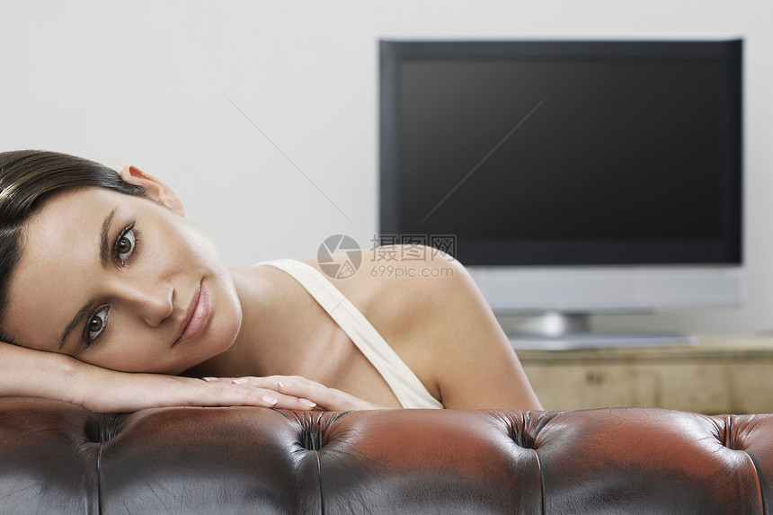 沙发上年轻女性在平板屏幕电视肖像前微笑摄影娱乐真皮女士成人黑发一人活动客厅图片