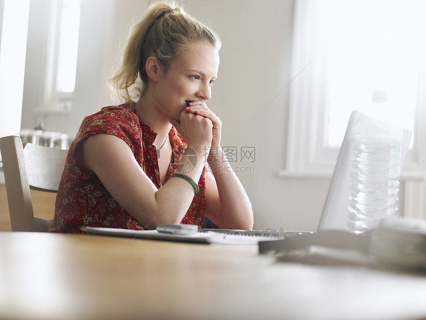 妇女使用膝上型电脑坐在餐桌低角度视图头发女士光线手肘幸福中年人服装双手中年马尾辫图片