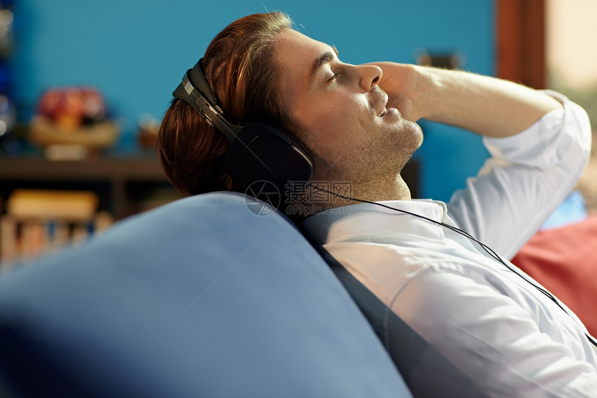 男用耳机听音乐的人爱好男性白色中年人眼睛享受耳机沙发衬衫立体声图片