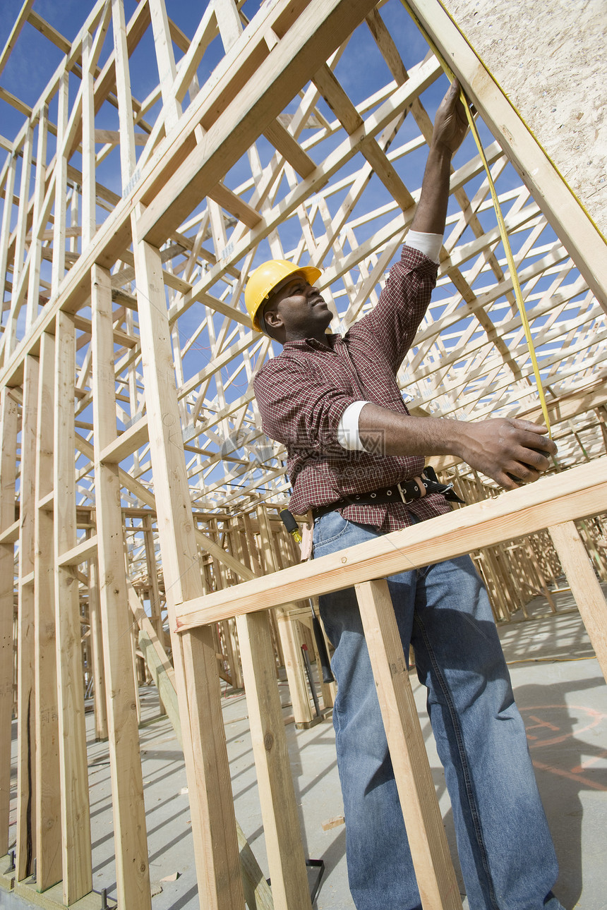 建筑施工工人测量大楼建设低角度建造业牛仔裤手臂建设者安全帽非裔框架技术建筑学图片