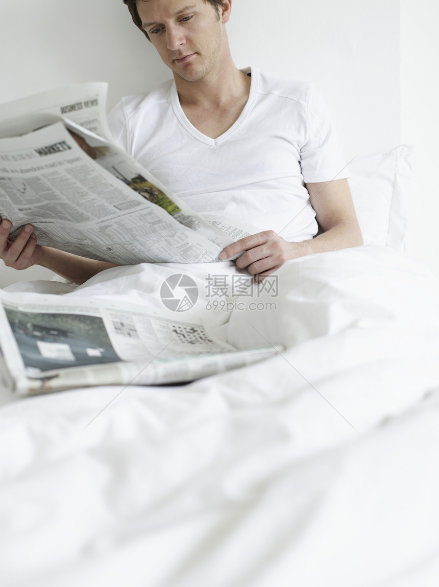 青年男子在床上阅读报纸成人头发成年家庭生活棕色一人卧室专注短发男人图片