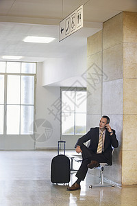 膝盖交叉双腿在机场使用移动电话的商务人士 商业人摄影成人大理石旅行一人航站楼电话双腿人士飞机场背景