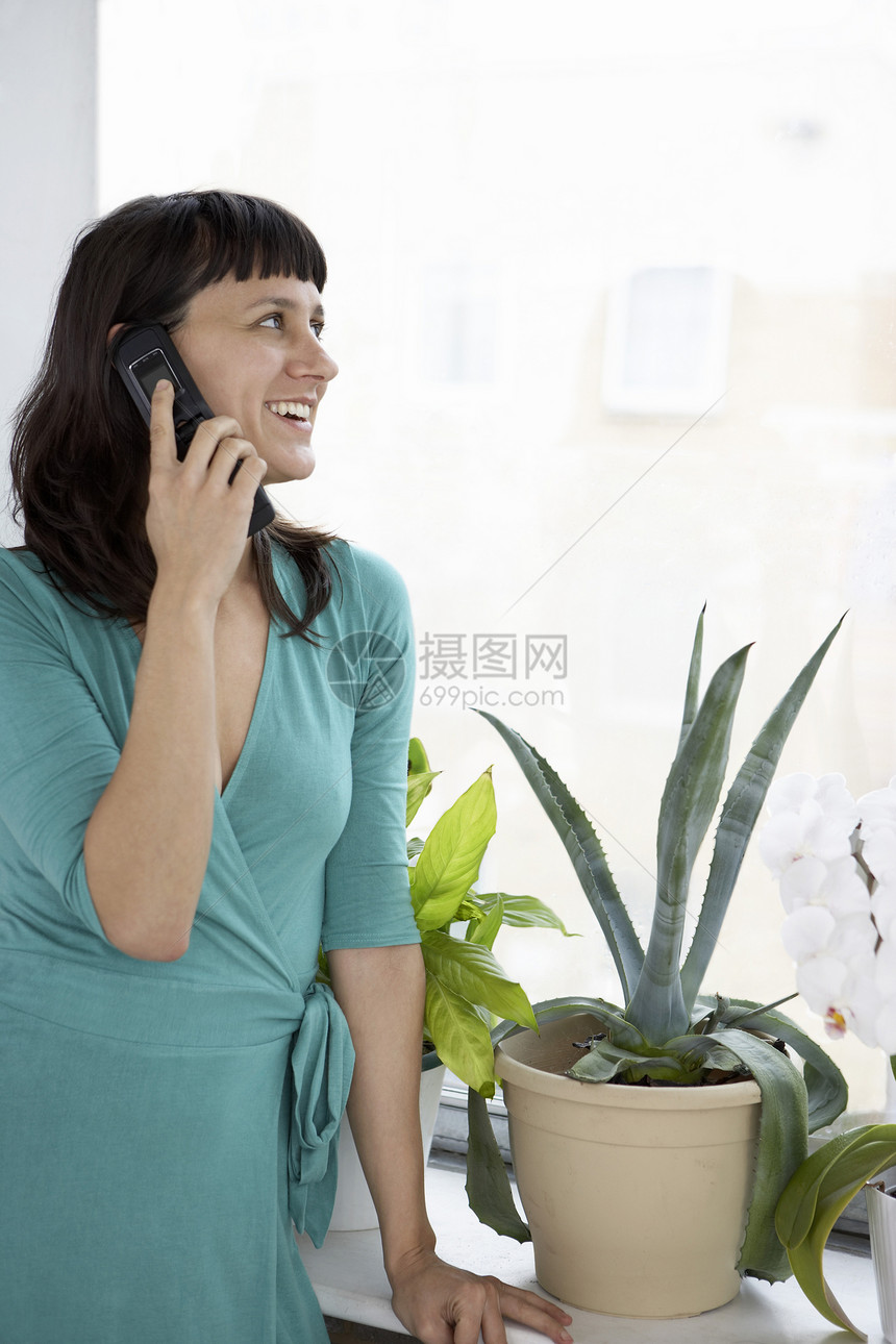 商业女商务人士用手机按工厂和窗户微笑图片