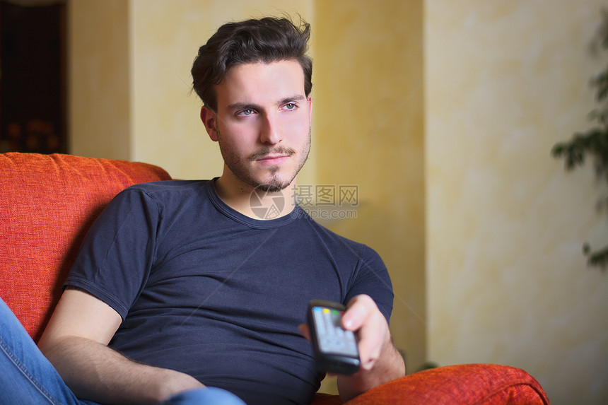 用电视遥控器 手用警棍的帅帅年轻男子控制长椅按钮技术男性电视沙发命令工作室男人图片