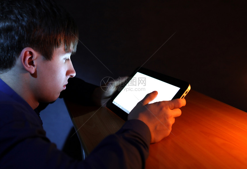 配有平板电脑的青少年照明桌子青年男人屏幕监视器互联网衬衫房间阅读图片