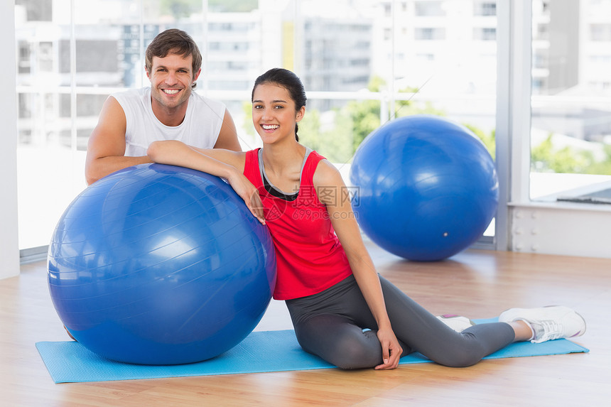 微笑和年轻情侣合身 在健身房有运动舞会运动服男人地面健身室健身活动训练身体女士混血图片