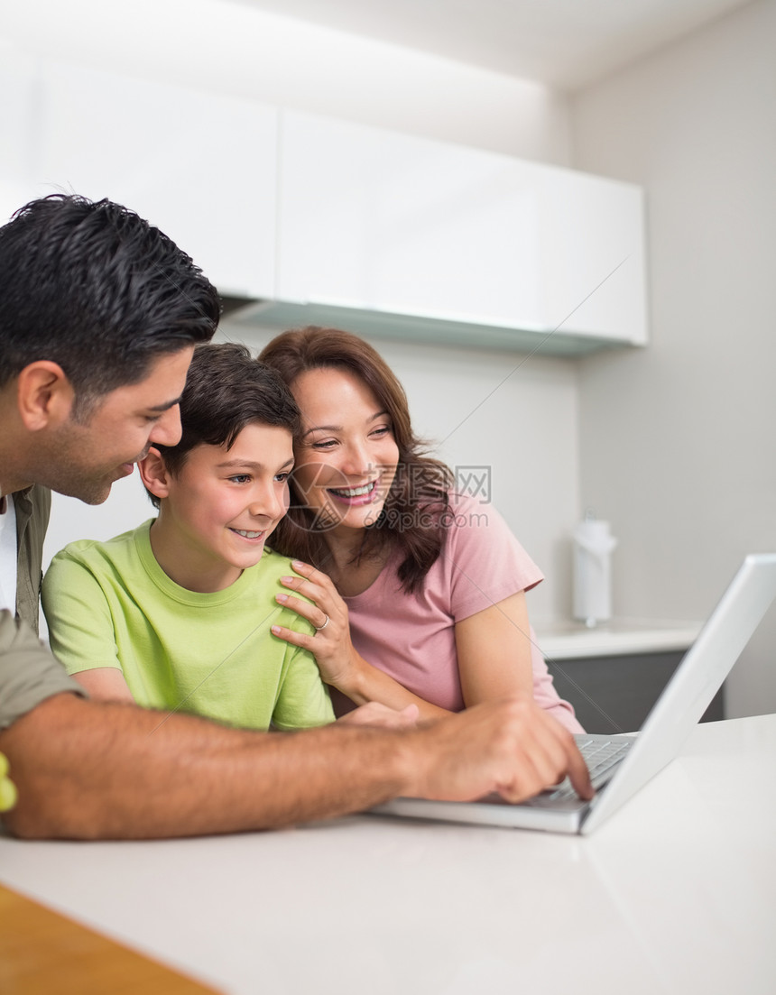 使用笔记本电脑与儿子一起微笑的一对夫妇团结母亲男人技术闲暇父亲男生家庭成人孩子图片