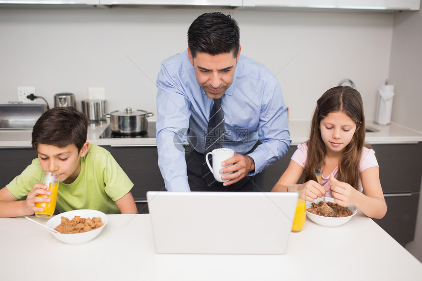 父亲使用笔记本电脑 孩子在厨房吃早餐男生房子女性橙汁儿子女孩女儿兄弟男人果汁图片