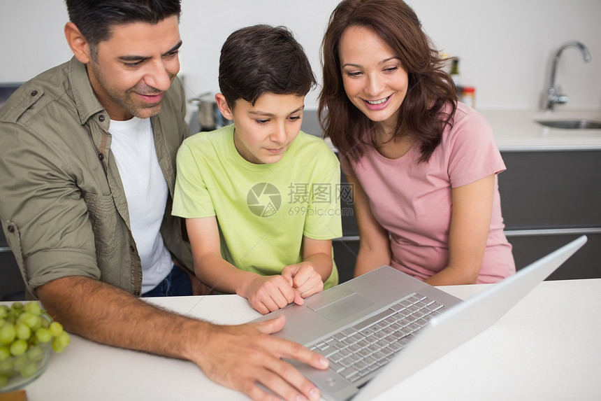 使用笔记本电脑与儿子一起微笑的一对夫妇成人学习团结父亲互联网技术母亲父母公寓房子图片