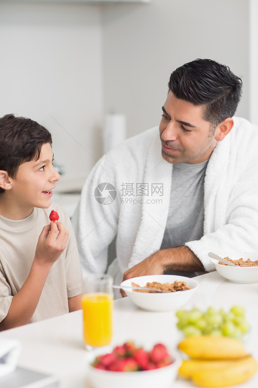 微笑的年轻儿子和父亲一起吃早餐图片