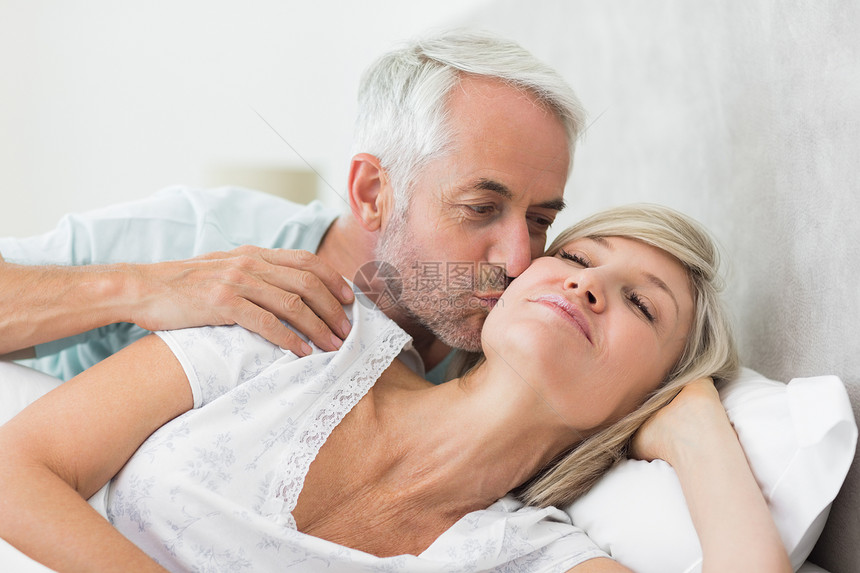 成年男子在床上亲吻女人的脸颊房子男性卧室软垫女性夫妻家庭生活睡眠休息觉醒图片