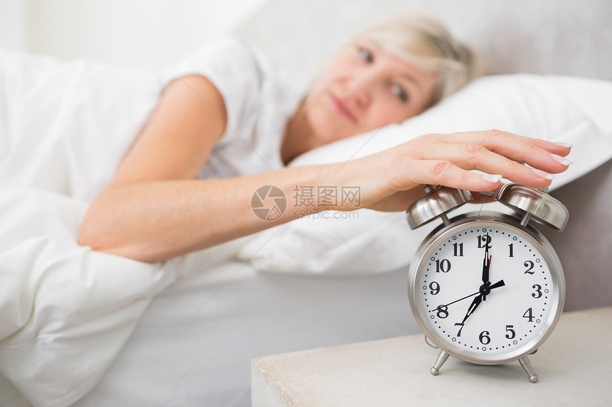 女人在床上伸手到闹钟睡眠卧室棉被铃声休息觉醒房子警报床单家庭生活图片