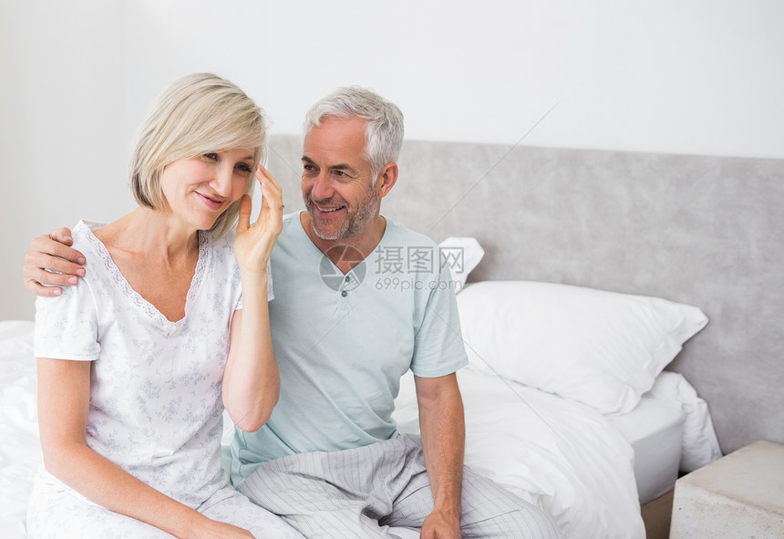 微笑的男人和女人坐在床上图片