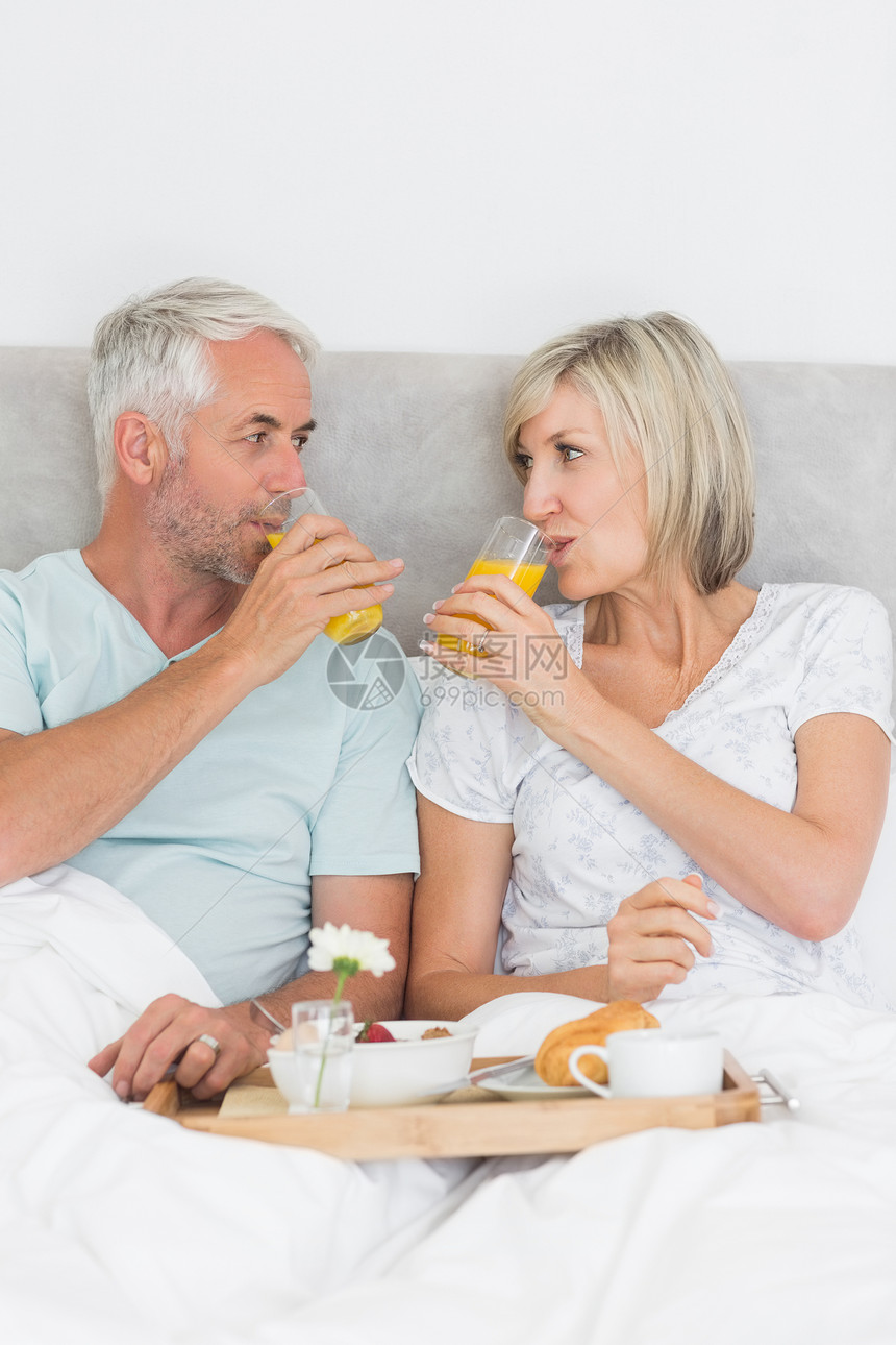 幸福的成熟夫妇在床上吃早餐食物托盘果汁橙汁软垫羽绒被枕头男人女性男性图片