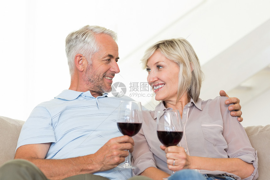 在沙发上坐着红酒杯的微笑成年夫妇长椅房子客厅女性玻璃家庭生活酒精男性夫妻男人图片