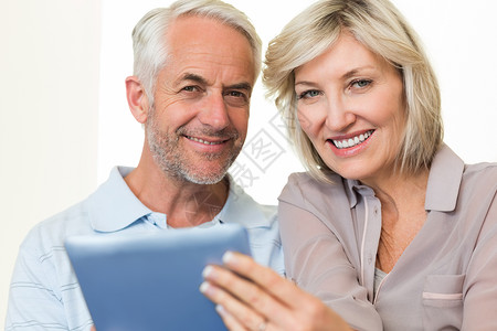 使用数字平板电脑特写笑笑的成熟夫妇背景图片
