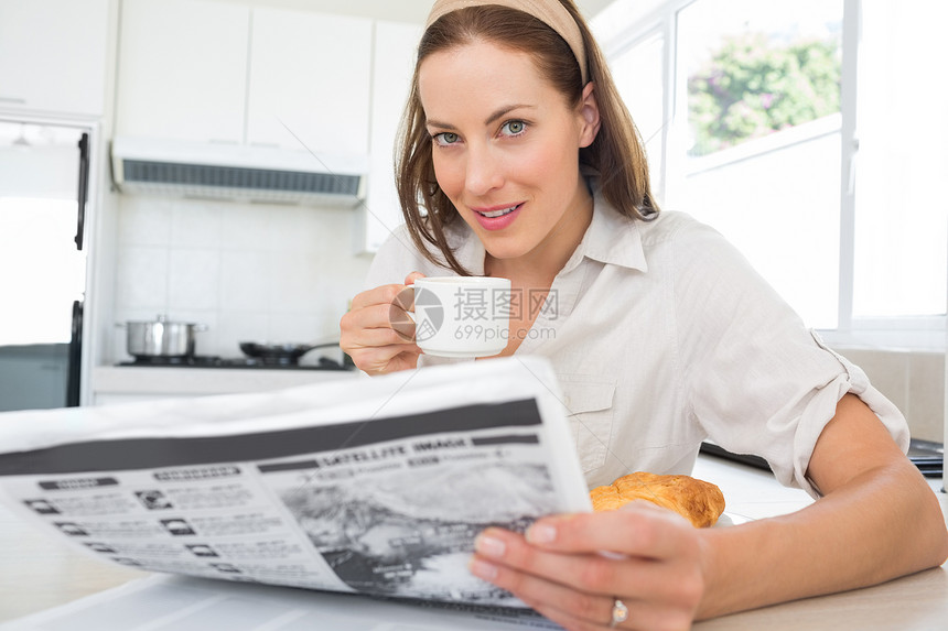 带咖啡杯和厨房报纸的笑女人;图片