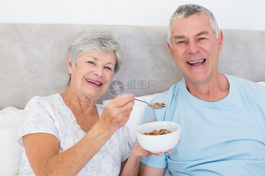 老年妇女向男子喂食谷类图片