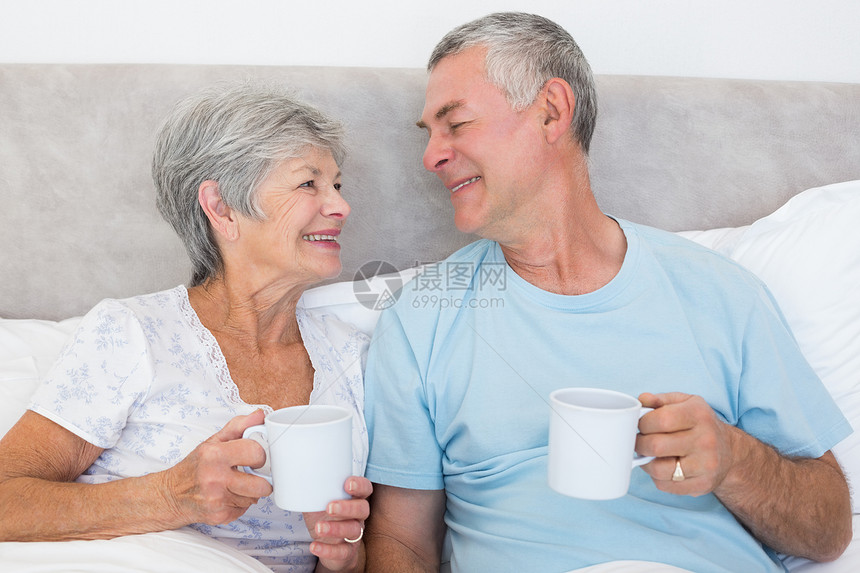 床上有咖啡杯的老年夫妇图片