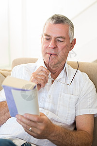 集中的人阅读书专注便服岁月退休成人男性男人客厅衬衫眼镜背景图片