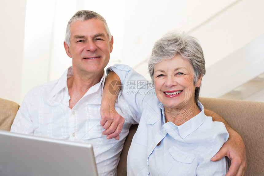 在沙发上有膝上型电脑的老年夫妇图片