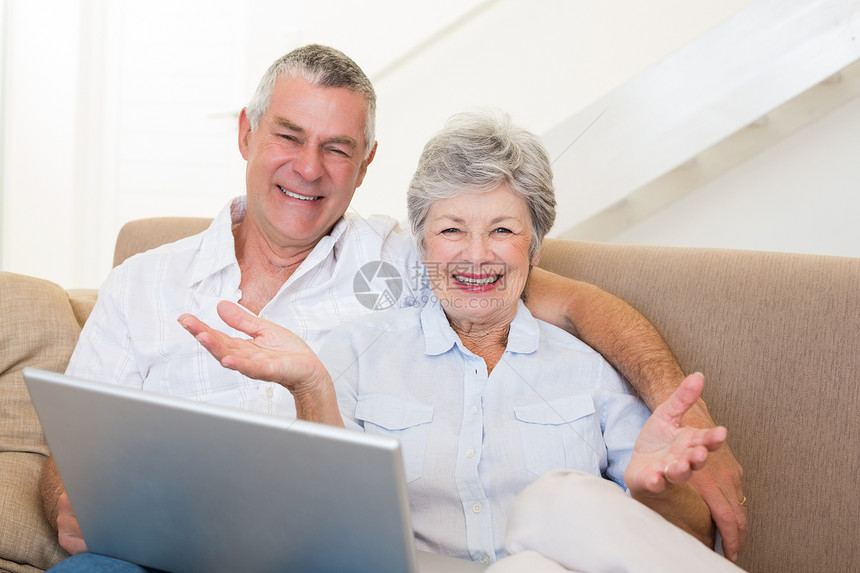 在沙发上有笔记本电脑的老年幸福情侣图片