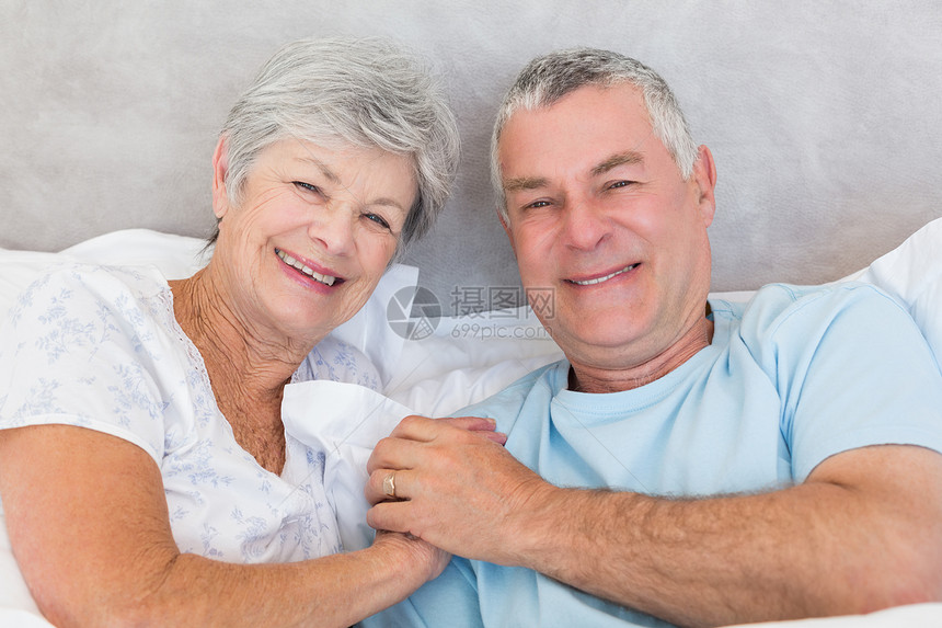 幸福的老年夫妇在床上牵手图片