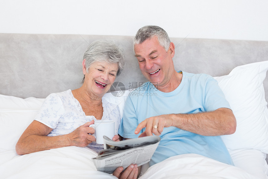 床上的老年夫妇阅读报纸图片