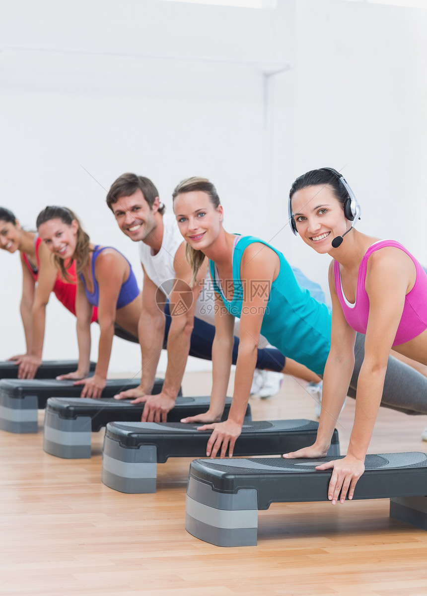 进行职级有氧运动的健身等级瘦身行动火车健身室女性团体训练健身房耳机俱乐部图片