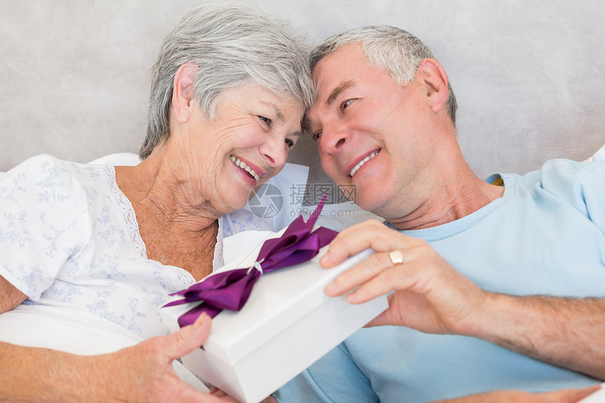 年长夫妇在床上交换礼品盒图片