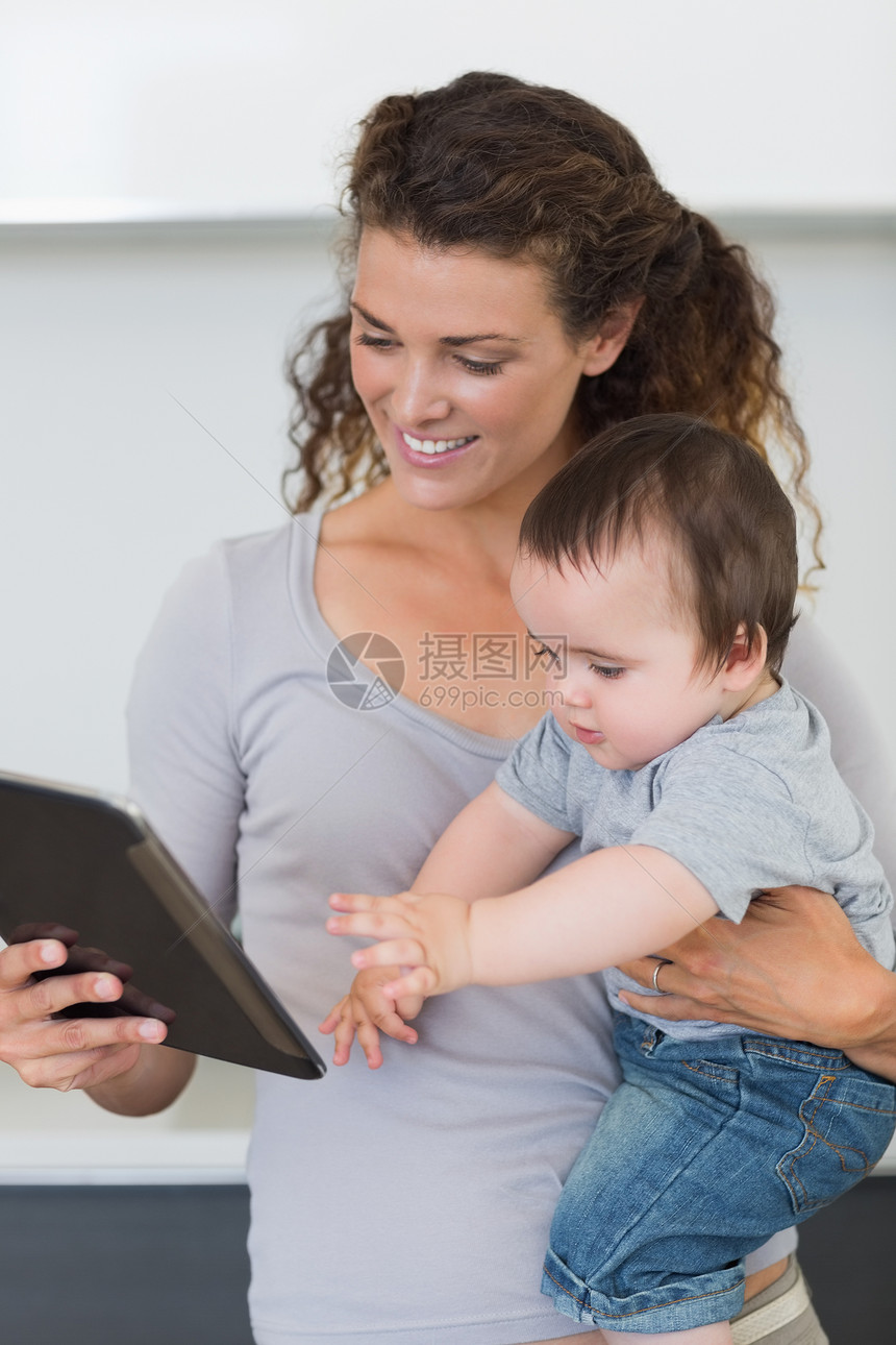 母亲在怀着婴儿时看数字平板电脑图片