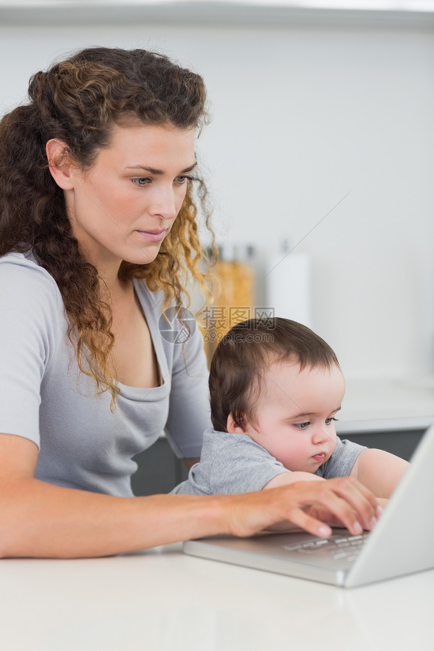 在柜台用笔记本电脑的怀有婴儿的妇女图片