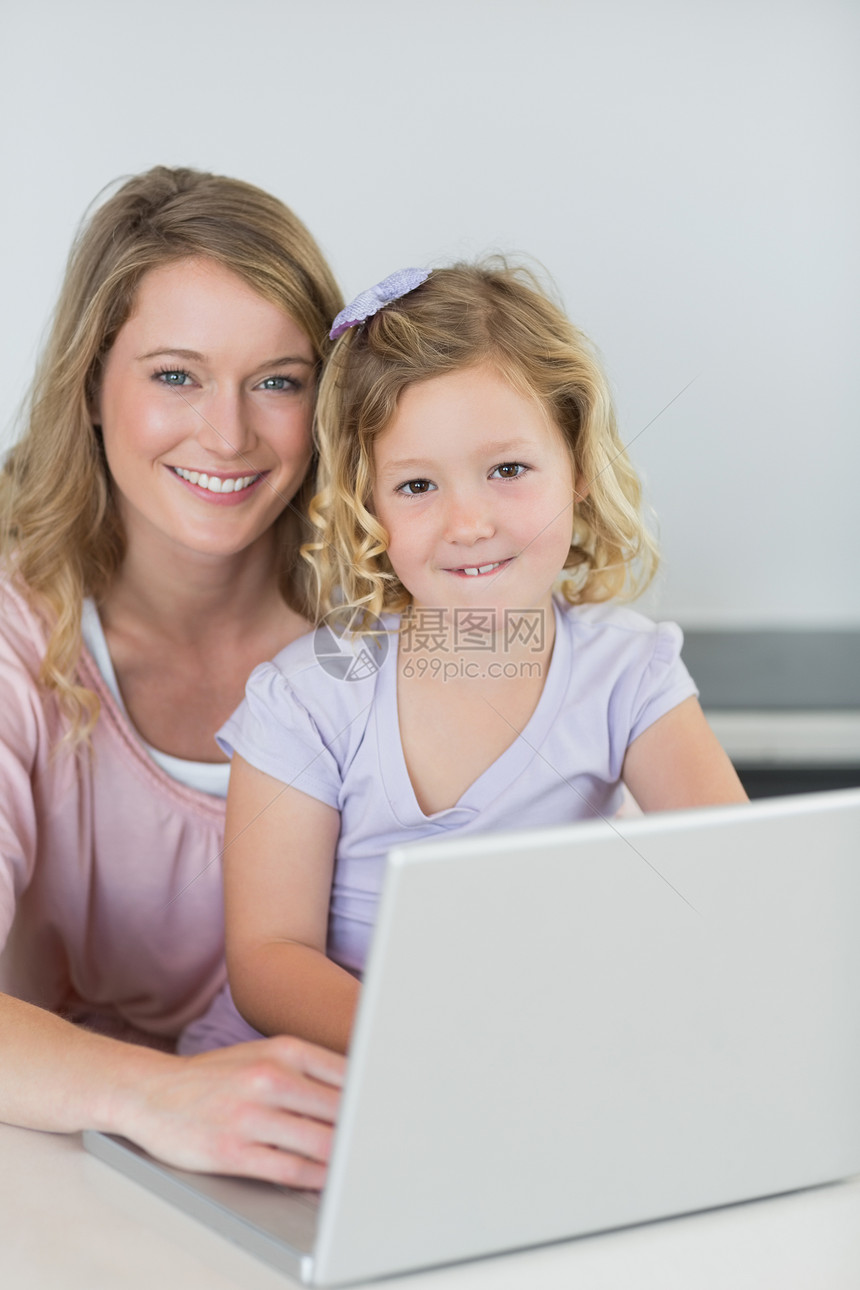 厨房桌上有笔记本电脑的母亲和女儿图片