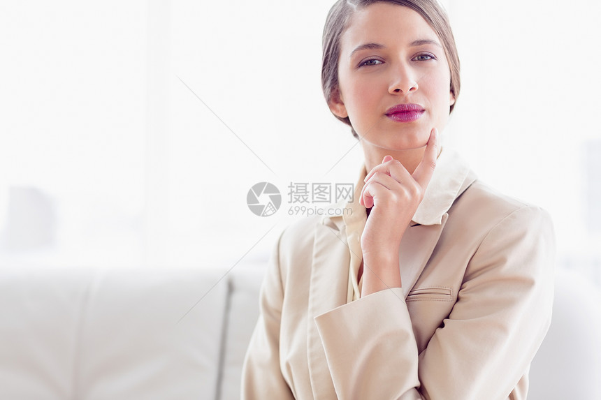 坐在沙发上的年轻思考女商务人士在看摄影机图片